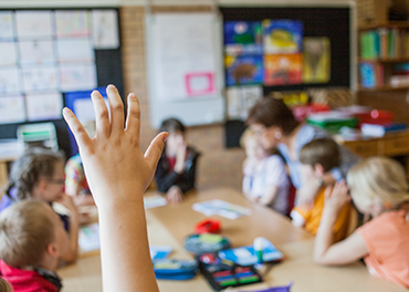 School child has raised a hand for solving query in a classroom