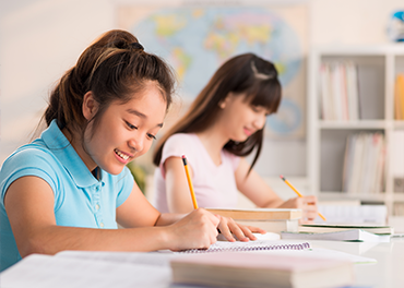 Two young girls are learning in a classroom