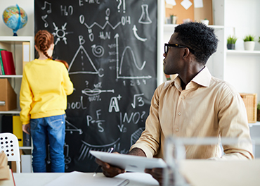 Teacher is writing something in a school blackboard